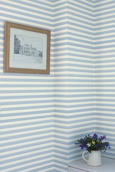 a blue and white striped wallpaper in a small room with a potted plant