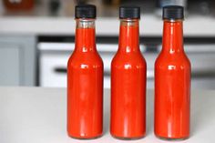 three red bottles sitting on top of a white counter