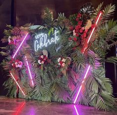 neon lights are lit up in the center of a floral display with palm leaves and flowers