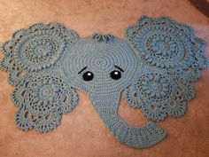 a crocheted elephant rug on the floor with an eye patch in the middle