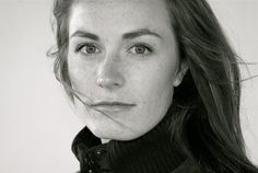 a black and white photo of a woman with freckles on her face looking at the camera