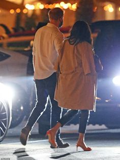 a man and woman walking down the street at night