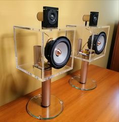 two speakers sitting on top of each other in front of a wooden table and yellow wall