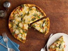 a pizza sitting on top of a wooden table next to a knife and fork with a slice missing from it