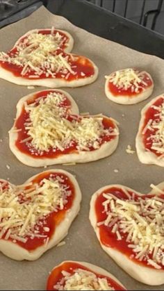 heart shaped pizzas with cheese and sauce in the shape of hearts on a baking sheet