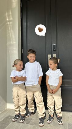 three young children standing in front of a door