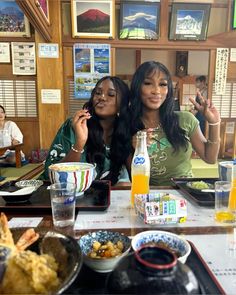 two women sitting at a table with food and drinks