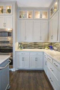 a large kitchen with white cabinets and wood flooring, along with stainless steel appliances