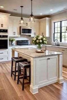 a large kitchen with an island and two stools in the center, along with white cabinets