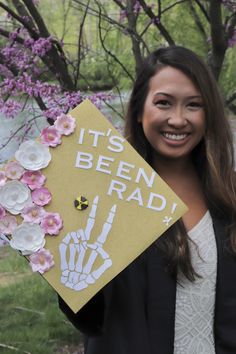 a woman holding up a graduation cap that says it's been rad