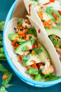 three tacos in a blue bowl with lettuce and carrots