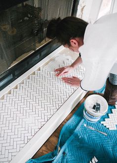 a woman is painting the floor with white paint