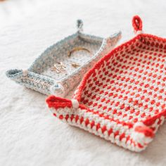 two crocheted trays sitting on top of a white bed next to each other