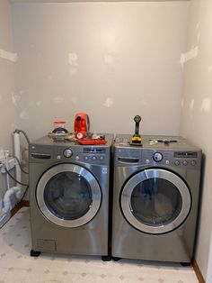 two washers sitting side by side in a room with dryer and dryer