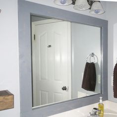 a bathroom mirror with two towels hanging from it's hooks on the wall next to a sink