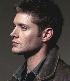 a man in a leather jacket looking off into the distance with his head tilted to the side