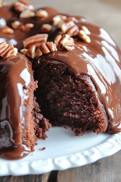 a chocolate bundt cake with pecans on top and one slice missing from it