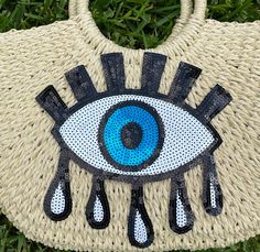 a woven purse with an evil eye on the front and blue eyes on the back