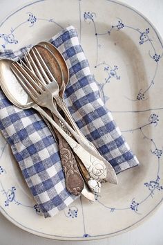 two forks and spoons sitting on top of a blue and white plate