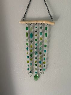 a wind chime hanging on the wall with beads and wood sticks attached to it