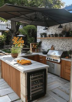 an outdoor kitchen with grill, sink and oven under an umbrella over the stove top