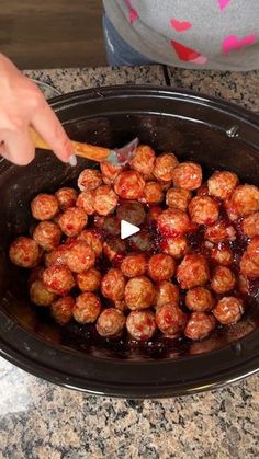 someone is stirring the meatballs in the slow cooker to make them look like they have been cooked