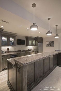 a large kitchen with an island in the middle and two lights hanging from the ceiling