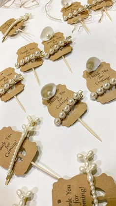 a table topped with lots of pins covered in white pearls and ribbones on top of brown tags