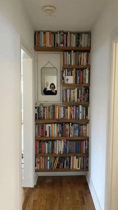 a bookshelf filled with lots of books next to a mirror on the wall