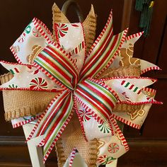 a christmas wreath made out of burlocks and ribbons on a stand in front of a door