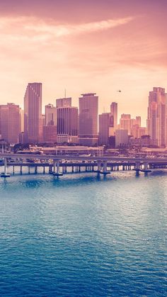 an image of a city skyline taken from the water's edge at sunset or sunrise