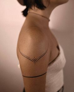 a woman with a tattoo on her shoulder is looking at the camera and has an arrow in it