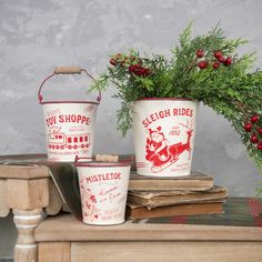 three white buckets with red designs on them sitting on a table next to a potted plant