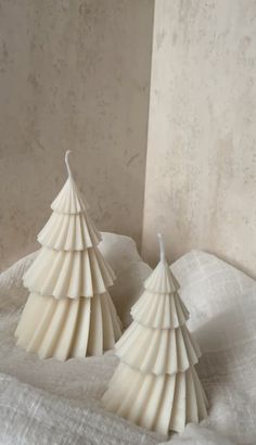 two white ceramic christmas trees sitting on top of a table