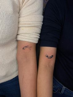 two people with matching tattoos on their arms, one is holding the other's arm