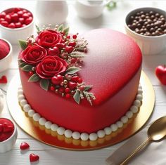 a heart shaped cake with red roses and berries on the top, surrounded by other desserts