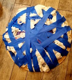 a round cake with blue ribbon on it sitting on top of a wooden table covered in paper