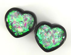 two black heart shaped earrings with green and pink flecks in them on a white background