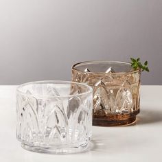 two clear glass candlesticks sitting next to each other on a white counter top