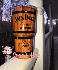 a wooden barrel sign sitting on top of a white railing next to flowers and trees