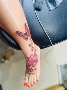 a woman's foot with a butterfly tattoo on her left leg and pink flowers in the foreground