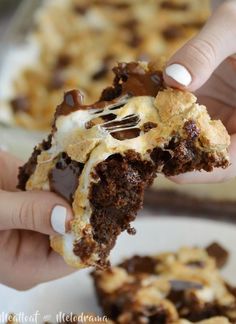 a person holding a piece of cake with chocolate and marshmallows on it