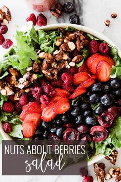 a bowl filled with berries and nuts on top of a white table next to a glass of milk