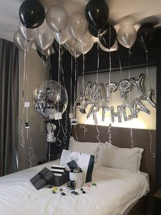 balloons and streamers are hanging from the ceiling above a bed in a room that is decorated for a birthday