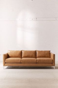 a tan leather couch against a white wall