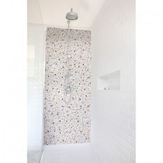 a white shower in a bathroom next to a wall with flowers on it and a faucet