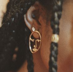 a close up of a person with ear rings on their ears and wearing braids