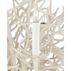 a candle that is sitting on top of a light fixture with white branches in the background