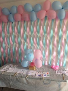 balloons and streamers decorate the backdrop for a baby's first birthday party