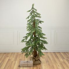 a small christmas tree in a room with wooden floors and white walls, wrapped presents under the tree